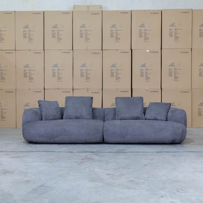 The Maven Curved Fabric Four Seat Sofa - Charcoal available to purchase from Warehouse Furniture Clearance at our next sale event.