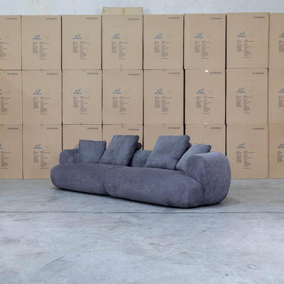 The Maven Curved Fabric Four Seat Sofa - Charcoal available to purchase from Warehouse Furniture Clearance at our next sale event.