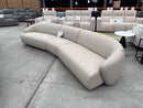 The COR-A0680 Curved 5 Seat Sofa - Oatmeal - Floor Stock available to purchase from Warehouse Furniture Clearance at our next sale event.