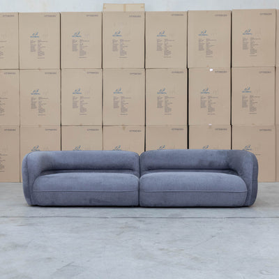 The Harper Curved Fabric Four Seat Sofa - Charcoal available to purchase from Warehouse Furniture Clearance at our next sale event.