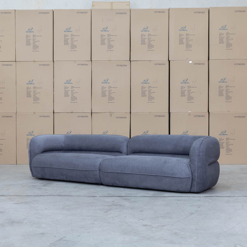 The Harper Curved Fabric Four Seat Sofa - Charcoal available to purchase from Warehouse Furniture Clearance at our next sale event.