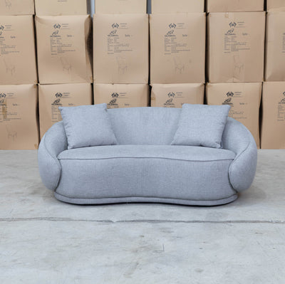 The Noosa Curved Fabric Two Seat Sofa - Light Grey available to purchase from Warehouse Furniture Clearance at our next sale event.