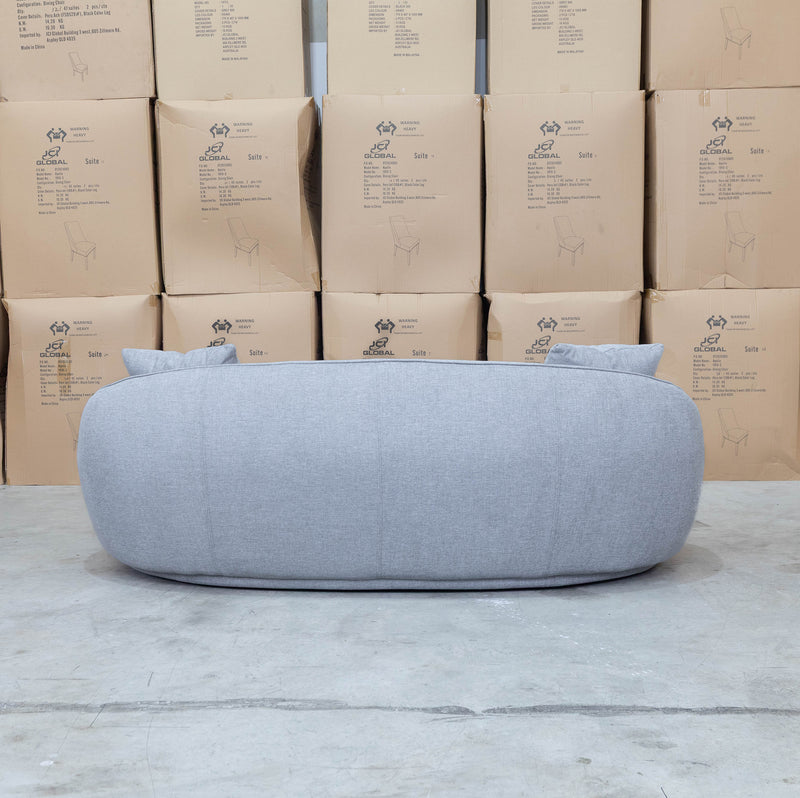 The Noosa Curved Fabric Three Seat Sofa - Light Grey available to purchase from Warehouse Furniture Clearance at our next sale event.